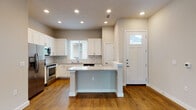 This well-designed single-floor home offers a clean, modern aesthetic throughout its open layout. The kitchen serves as a central highlight, featuring white shaker cabinetry, a classic subway tile backsplash, granite countertops, and a central island ideal for casual dining or meal prep. Stainless steel appliances — including a refrigerator, range, microwave, and dishwasher — complete the functional space. A front entry door with a transom window floods the kitchen and entry area with natural light.

Warm hardwood flooring extends throughout the home, creating a cohesive and inviting atmosphere. The spacious living area includes a ceiling fan and sliding glass doors that open to an outdoor patio, offering views of a fenced backyard. Multiple bedrooms are well-proportioned, each featuring hardwood floors, neutral-toned walls, and windows with blinds that allow for controlled natural light.

The bathrooms are thoughtfully finished, with one featuring a granite-topped white vanity with under-mount sink, and another showcasing a soaking tub surrounded by large-format, wood-grain ceramic tile. Clean white trim and neutral wall tones tie the entire space together, giving the home a fresh and move-in-ready feel.