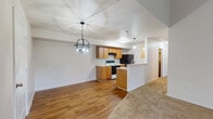This single-floor residence offers an open-concept design that seamlessly connects the living, dining, and kitchen areas. The living room is a standout space, featuring soaring vaulted ceilings that amplify the sense of openness, neutral carpet flooring, a built-in fireplace with a niche above, and a sliding glass door that invites natural light. A decorative globe pendant chandelier adds a stylish focal point to the dining area, which transitions smoothly onto hardwood-style flooring shared with the kitchen.

The kitchen is well-equipped, featuring warm honey-toned cabinetry, light countertops, a coil-top electric range, black refrigerator, dishwasher, and an under-cabinet range hood. A peninsula breakfast bar with matching cabinetry provides an additional prep and seating surface, reinforcing the open flow between kitchen and living spaces.

The bedroom offers plush carpet flooring and includes access to a dedicated walk-in closet with a built-in hanging rod, providing ample storage. Both bathrooms are functionally appointed with full-size tub and shower combinations, hardwood-style floors, and clean white fixtures, conveying a practical and consistent aesthetic throughout the home.