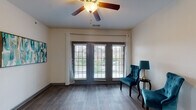 Located at 377 Athens Way in Nashville, Tennessee, this single-floor residence offers a well-designed layout with consistent finishes throughout. The living area features wood-style plank flooring, a ceiling fan, and a set of French doors framed by white curtains that allow an abundance of natural light and provide access to an outdoor balcony. An adjacent dining area is highlighted by a stylish chandelier and flows directly into the kitchen. The galley-style kitchen is well-appointed with gray cabinetry, granite-style countertops, white appliances including a range, refrigerator, built-in microwave, and dishwasher, along with a window that brings in additional natural light. The bedrooms are carpeted for comfort, each featuring ceiling fans and ample closet space, including walk-in and mirrored sliding-door closets. The bathrooms continue the cohesive design aesthetic with gray vanity cabinetry, granite countertops, large mirrors, and wood-style flooring. One bathroom includes a window for natural ventilation. Throughout the space, gray door and window trim provides a clean, modern contrast against the neutral wall tones, creating a cohesive and inviting atmosphere.