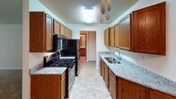Located at 4101 W 98th St in Bloomington, Minnesota, this single-floor unit offers a functional and straightforward layout designed for comfortable everyday living. The space is organized to maximize usability, with each area flowing naturally into the next.

The living area is generously sized, featuring neutral-toned carpet, a textured ceiling, and a large sliding glass door dressed with vertical blinds that floods the room with natural light and offers outdoor views. A wall-mounted air conditioning unit and baseboard heating ensure year-round comfort. An adjacent hallway connects the main living space to the private areas of the unit.

The galley-style kitchen is a standout feature, lined on both sides with warm wood cabinetry and topped with granite-patterned countertops. A double stainless steel sink, gas range with oven, built-in microwave, and refrigerator complete the kitchen's practical setup. Tile flooring and a ceiling fan add to the room's functionality.

The bedrooms are carpeted and bright, each offering closet storage with sliding doors and wire shelving systems. The full bathroom includes a tub-shower combination with a clean white surround, a vanity with mirror, and neutral finishes throughout. Overall, the unit presents a clean, practical living environment suited for a variety of lifestyles.