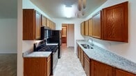 Located at 4101 W 98th St in Bloomington, Minnesota, this single-floor unit offers a functional and straightforward layout designed for comfortable everyday living. The space is organized to maximize usability, with each area flowing naturally into the next.

The living area is generously sized, featuring neutral-toned carpet, a textured ceiling, and a large sliding glass door dressed with vertical blinds that floods the room with natural light and offers outdoor views. A wall-mounted air conditioning unit and baseboard heating ensure year-round comfort. An adjacent hallway connects the main living space to the private areas of the unit.

The galley-style kitchen is a standout feature, lined on both sides with warm wood cabinetry and topped with granite-patterned countertops. A double stainless steel sink, gas range with oven, built-in microwave, and refrigerator complete the kitchen's practical setup. Tile flooring and a ceiling fan add to the room's functionality.

The bedrooms are carpeted and bright, each offering closet storage with sliding doors and wire shelving systems. The full bathroom includes a tub-shower combination with a clean white surround, a vanity with mirror, and neutral finishes throughout. Overall, the unit presents a clean, practical living environment suited for a variety of lifestyles.