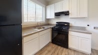 This single-story residence presents a clean, neutral aesthetic throughout, with consistent finishes that create a cohesive and practical living environment. The kitchen is equipped with white shaker-style cabinetry, dark speckled countertops, a stainless steel sink positioned beneath a window that allows natural light to fill the space, and a black gas range with an overhead exhaust hood. Wood-look plank flooring runs through the kitchen and connects to adjoining living areas, lending warmth and durability underfoot.

The bedrooms feature plush gray carpeting and are well-lit by multiple windows fitted with horizontal blinds, providing both brightness and privacy. Each room offers a comfortable sense of space with clean white walls and simple, functional layouts.

Two full bathrooms serve the unit, both finished with wood-look flooring, white fixtures, and tub-shower combinations. One bathroom includes a vanity with a white sink, cabinet storage, and a large mirror, while the other maintains a similarly bright and utilitarian design.

The overall floor plan, as seen in the 3D model, is compact yet well-organized, with defined separate rooms and clear circulation between spaces. The consistent use of light tones and natural light throughout gives the unit an open, airy ambiance.