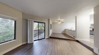 This single-floor residence offers a clean, modern aesthetic with a thoughtfully designed open layout. The main living area is anchored by durable wood-look flooring and features a ceiling fan, a textured ceiling, and a sliding glass door that opens to a private deck with views of surrounding greenery — filling the space with natural light. A raised step separates the living and dining zones, adding architectural interest while maintaining an open, connected feel. A pass-through counter links the living area directly to the kitchen, which is well-equipped with white shaker cabinetry, light countertops, a stainless steel sink, a dishwasher, and stainless appliances including a refrigerator and electric range. The bedrooms feature plush carpeting, large windows that invite natural light and outdoor views, and neutral walls that lend a calm, versatile atmosphere. The bathrooms are finished with white cabinetry, undermount sinks, light quartz-style countertops, brushed nickel fixtures, and a full tub-shower combination. Throughout the space, a consistent neutral color palette, crisp white trim, and updated finishes create a cohesive and move-in-ready environment.