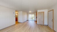Located at 133 N 29th Ave in Cornelius, Oregon, this single-floor, 2-bedroom, 2-bathroom home offers a practical and comfortable layout. Light wood flooring flows throughout the main living areas, lending a clean and cohesive aesthetic, while a central hallway connects all rooms efficiently.

The spacious living room is bright and open, benefiting from natural light through a large sliding glass door that leads to an outdoor area. The combined dining and kitchen space features warm-toned wood cabinetry with ample upper and lower storage, dark countertops, and white appliances including a range and refrigerator — all set on matching wood-look flooring.

Both bedrooms are carpeted and well-lit by windows with vertical blinds that frame views of the surrounding greenery. The primary bedroom offers a generous footprint with multiple closets for added storage. Each bathroom includes a vanity with wood cabinetry, dark countertops, and a wall-mounted mirror with overhead lighting.

A dedicated laundry room includes washer/dryer hookups, wire shelving, and a water heater, providing functional utility space. With five closets throughout, storage is plentiful. The home's neutral color palette, light flooring, and consistent finishes create a clean, move-in-ready environment.