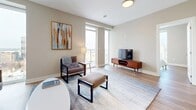 This thoughtfully designed two-bedroom, two-bathroom residence in London, Ontario offers a comfortable and contemporary living experience across a single well-planned floor. Warm hardwood-style flooring flows throughout, complementing the neutral tones that give the space a clean, modern aesthetic.

The kitchen is a standout feature, boasting crisp white cabinetry, classic subway tile backsplash, a large central island with a quartz-style countertop, and a full suite of stainless steel appliances, including a French door refrigerator, range, built-in microwave, and dishwasher. Pendant and track lighting add a polished finish.

The open living room is filled with natural light from floor-to-ceiling windows that also provide access to a private balcony, offering elevated city views. The space is well-proportioned and inviting.

The primary bedroom features dramatic tall windows framing panoramic urban views, creating a bright and airy retreat. A dedicated walk-in closet provides generous storage. The ensuite bathroom includes a sleek glass-enclosed shower with marble-style tile surround. The second bedroom is equally comfortable, conveniently positioned near the second full bathroom, which features a soaking tub with a matching marble-style tile surround. The overall ambiance is clean, bright, and move-in ready.