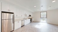 Located at 1503 E Venice Blvd in Los Angeles, this modern one-bedroom, one-bathroom unit offers a thoughtfully designed single-floor layout with clean, contemporary finishes throughout. The open-concept kitchen and living area forms the heart of the unit, featuring floor-to-ceiling white cabinetry, light-toned countertops, and a full suite of stainless steel appliances including a refrigerator, dishwasher, gas range, and microwave. Recessed lighting and a large window flood the living space with natural light, creating a bright and airy atmosphere. The patterned tile flooring extends seamlessly throughout the main living areas, contributing to the cohesive, modern aesthetic. The bedroom is comfortably sized, offering a large floor-to-ceiling window with views of the surrounding neighborhood, recessed lighting, and direct access to both the bathroom and a dedicated closet. The bathroom is outfitted with a soaking tub, a floating white vanity with an integrated sink, a mirrored medicine cabinet with storage, and matching tile flooring. A dedicated laundry area with a stacked washer and dryer adds everyday convenience. The unit's clean white walls, modern hardware, and abundant natural light create a fresh, move-in-ready living space in the heart of Venice.