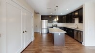 Located at 140 Hanton Rd in North Smithfield, Rhode Island, this single-floor residence offers a well-designed layout with thoughtfully finished interiors throughout. The kitchen serves as a central highlight, showcasing rich dark cabinetry that extends to the ceiling, granite countertops, a white subway tile backsplash, and stainless steel appliances including a refrigerator, range, and built-in microwave. A center island with pendant lighting provides additional prep space and a casual gathering point, while warm hardwood-style flooring ties the kitchen area together seamlessly.

The bedrooms feature neutral wall-to-wall carpeting and multiple windows that invite abundant natural light and frame views of the surrounding wooded landscape. One bedroom opens to a balcony, further enhancing the connection to the outdoors.

The bathrooms are finished with dark cabinetry complementing white countertops and black-and-white mosaic tile flooring. The primary bathroom includes a double-sink vanity with brushed nickel fixtures and a well-lit mirror, while the secondary bathroom offers a full tub and shower combination. A dedicated in-unit laundry closet with a stacked washer and dryer adds everyday convenience. The overall ambiance is clean, modern, and move-in ready.