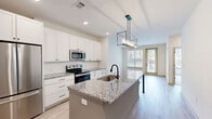 Located at 2250 Oak Road Southwest in Snellville, GA, this well-appointed one-bedroom, one-bathroom residence offers a thoughtfully designed single-floor layout that maximizes functionality and style. The open-concept kitchen serves as the centerpiece of the unit, showcasing crisp white shaker cabinetry extending to the ceiling, granite countertops, and a large island with an undermount sink and a striking geometric pendant light fixture. Stainless steel appliances — including a French door refrigerator, electric range, and built-in microwave — complement the clean, contemporary aesthetic. Light-toned hardwood-style flooring flows throughout the main living areas, enhancing the sense of openness and brightness. The living area features a ceiling fan and direct access to a private patio through a glass-paneled door, flooding the space with natural light and offering outdoor views. The bedroom is carpeted for comfort, with a generous window that brings in additional natural light. A dedicated laundry area houses a stacked washer and dryer unit, adding everyday convenience. Recessed lighting throughout the common areas and kitchen provides consistent, clean illumination. The overall design palette — neutral tones, modern fixtures, and quality finishes — creates a cohesive and inviting atmosphere throughout.