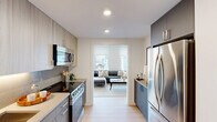 This thoughtfully designed one-bedroom, one-bathroom residence offers a compact yet functional layout spread across a single floor. The galley-style kitchen is outfitted with stainless steel appliances, including a full-size refrigerator, electric range, built-in microwave, and dishwasher. Two-toned cabinetry — combining warm wood-finish uppers with sleek gray lowers — frames dark countertops, creating a contemporary and polished aesthetic. Recessed lighting illuminates the space efficiently throughout.

The living room is bright and open, benefiting from large windows that invite abundant natural light and offer urban views of the surrounding cityscape. Light hardwood-style flooring runs continuously through the main living areas, contributing to a cohesive and airy feel. A dedicated dining nook provides additional functionality within the living space.

The bedroom features dual windows overlooking the city, allowing natural light to fill the room, and includes access to a dedicated closet. The bathroom is finished with neutral tile surrounding the shower-tub combo, complemented by clean white fixtures for a timeless look.

Overall, the residence presents a modern, minimalist design with a neutral color palette, making it a well-appointed and efficient urban living space.