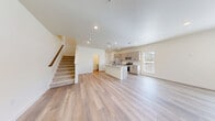 Located at 621 Homestead Avenue in Brighton, CO, this contemporary two-story home offers a thoughtfully designed layout across two floors. The main level features an open-concept kitchen and living area bathed in natural light from multiple windows. The kitchen is a standout, showcasing light wood cabinetry, a granite-topped center island with an undermount sink, stainless steel appliances including a French door refrigerator, electric range, and microwave, plus a classic tile backsplash. Light wood-tone luxury vinyl plank flooring flows throughout the main level, complementing the neutral palette. A convenient half-bath is also located on this floor. A carpeted staircase leads to the upper level, where two well-sized bedrooms offer plush carpet, multiple windows with neighborhood views, and generous closet space, including a walk-in closet in the primary bedroom. The upper level hosts two full bathrooms, including a primary bath featuring a glass-enclosed walk-in shower, a dual-sink vanity with bold blue cabinetry, and a window for natural light. Four closets total provide ample storage throughout the home. Clean lines, recessed lighting, and a bright, neutral color scheme give the entire space a fresh, move-in-ready feel.