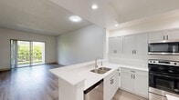 Located in West Palm Beach, FL, this well-appointed single-story residence offers 2 bedrooms and 3 bathrooms across a thoughtfully designed floor plan. Light wood-look flooring flows throughout, complemented by crisp white walls and recessed lighting that create a clean, modern aesthetic.

The open-concept living and dining area is bathed in natural light, with large sliding glass doors leading to a private patio and lush outdoor views. The kitchen features white shaker-style cabinetry with matte black hardware, gleaming quartz countertops, a peninsula with a double-basin sink, and stainless steel appliances including a dishwasher. A galley-style layout provides ample prep and storage space.

A hallway connects the main living areas to the bedrooms and den. The spacious primary bedroom offers high ceilings, an en-suite bathroom, and generous closet space. The second bedroom includes a ceiling fan and a window with green outdoor views. Three bathrooms are finished in a clean, minimalist style, with at least one featuring a full soaking tub and shower combo with matte black fixtures. The home also includes a dedicated laundry area, a den, and an impressive nine closets, providing exceptional storage throughout.