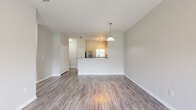 Located at 4017 Crosswind Court in Melbourne, FL, this single-story, one-bedroom, one-bathroom residence offers a thoughtfully designed layout with efficient use of space. The open-concept living and kitchen area serves as the heart of the home, where wood-look laminate flooring flows seamlessly throughout. A pendant light fixture hangs over the kitchen peninsula, which features dark granite-style countertops and doubles as a breakfast bar. The kitchen is well-appointed with white shaker-style cabinetry, a full suite of stainless steel appliances including a refrigerator, electric range, built-in microwave, and dishwasher. The adjacent living area is bright and airy, with a ceiling fan and sliding glass doors that open to an outdoor view of lush greenery, filling the space with natural light. The spacious primary bedroom is carpeted for comfort, includes a ceiling fan, a large window overlooking the outdoors, and a closet. The bathroom features wood-look flooring, a vanity with dark countertops, a large mirror, and grab bars for added accessibility. Clean neutral tones and white trim throughout create a cohesive, move-in-ready aesthetic.