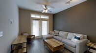 Located at 722 Island Park Dr. on Daniel Island, SC, this single-story residence offers a thoughtfully designed interior that blends comfort with contemporary style. The living area serves as the heart of the home, showcasing dark hardwood flooring that anchors the space with warmth and sophistication. A bold, deep-toned accent wall adds depth and contrast against the neutral surrounding walls, creating a modern yet inviting atmosphere. Natural light pours in through French doors fitted with transom windows above, bringing the outdoors in while providing access to the exterior. A ceiling fan with a light fixture enhances airflow and comfort, while track lighting along the ceiling offers additional illumination. The living space is generously proportioned, comfortably accommodating a large sectional sofa, a leather accent chair, and a rustic wood-and-metal coffee table that adds an industrial touch. The overall design aesthetic is cohesive and refined, blending earthy tones, natural textures, and modern furnishings to create a space that feels both stylish and livable. This Daniel Island property delivers a compelling combination of location, design, and single-level convenience.