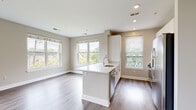 This well-appointed single-floor residence showcases a thoughtfully designed open-concept layout that seamlessly integrates the kitchen, dining, and living areas. The living space is bathed in natural light through an expansive arrangement of double-hung windows fitted with clean white blinds, offering pleasant views of surrounding greenery and the neighboring streetscape. Rich hardwood-style flooring flows throughout the main living areas, lending warmth and continuity to the space.

The kitchen is a standout feature, centered around a sleek white island with a built-in sink and light quartz countertops. It is equipped with stainless steel appliances, including a gas range, overhead microwave, dishwasher, and refrigerator. A subway tile backsplash in soft sage tones adds a refined, contemporary touch, complemented by crisp white cabinetry.

The bedrooms are generously proportioned, each carpeted for comfort and featuring windows that draw in natural light and outdoor views. The two full bathrooms maintain a consistent, clean aesthetic, with white subway tile surround tub-shower combinations, hardwood-style flooring, and chrome fixtures throughout.

Neutral warm-gray walls, recessed lighting, and clean white baseboards and trim unify the space, creating a bright, modern ambiance that is both functional and inviting.