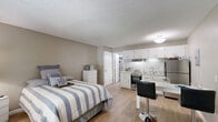 Located at 9300 Montana Ave in El Paso, TX, this efficiently designed studio unit makes excellent use of its single-floor layout. The open-concept living and sleeping area features warm wood-look flooring, neutral-toned walls, and a textured ceiling, creating a clean and cohesive atmosphere throughout.

The kitchen is thoughtfully outfitted with white cabinetry extending to the upper walls, a mosaic tile backsplash, stainless steel appliances including a refrigerator and electric range, a double-basin sink, and light granite-style countertops. A small dining area with a bar-height table and seating sits adjacent to the kitchen, maximizing the use of available space.

The unit includes two bathrooms, providing a practical convenience. One bathroom features a tub-shower combination with tile surround in neutral tones, while a connecting hallway links the bathrooms and living areas with continuity. A built-in closet with shelving offers additional storage.

Natural light enters through a window at the front of the unit near the entry door, brightening the living and sleeping area. The overall design emphasizes functionality and a clean aesthetic, making this a well-organized and practical space suited for everyday living.