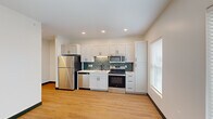 Located at 4591 McRee Ave in St. Louis, Missouri, this one-bedroom, one-bathroom unit offers a thoughtfully designed single-floor layout with a clean, modern aesthetic throughout. Light-toned hardwood-style flooring and crisp white walls create a bright, cohesive feel across every room.

The kitchen is a standout feature, showcasing white shaker-style cabinetry extending to the ceiling, a teal subway tile backsplash, white quartz countertops, and a full suite of stainless steel appliances including a refrigerator, electric range, microwave, and dishwasher. A matte black faucet and hardware add a contemporary contrast. Natural light filters in through a sizable window with blinds.

A central hallway connects the rooms efficiently, with recessed lighting overhead and a walk-in closet conveniently accessible off the corridor. The bedroom is a well-proportioned, serene space with a ceiling fan, ample natural light, and its own walk-in closet with wire shelving.

The bathroom continues the modern design language with white cabinetry, a single undermount sink, matte black fixtures, a large mirror with vanity lighting, and grab bars for added accessibility. The living area provides an open, flexible space suited for a variety of furniture arrangements. Bold dark baseboards throughout the unit provide a clean, finished border to the warm flooring.