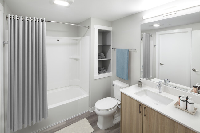 Phase II - Scheme D Bath with oak cabinetry, white quartz countertop, and hard surface flooring - Avalon Newcastle Commons