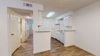 Located at 1168 N Douglas Blvd in Midwest City, Oklahoma, this single-floor unit offers a functional and well-maintained layout with consistent finishes throughout. The entryway opens into a dining area adorned with an elegant chandelier and warm wood-look flooring that extends through the main living spaces, creating a cohesive and inviting atmosphere.

The kitchen is designed in a galley style, featuring white cabinetry with ample storage, white appliances including a refrigerator, electric range, and dishwasher, along with a stainless steel sink. A peninsula with a breakfast bar provides additional counter space and creates a natural divide between the kitchen and the adjacent living areas. A textured ceiling and efficient overhead lighting complete the kitchen's clean, practical aesthetic.

The bedrooms are carpeted for comfort and each feature ceiling fans with light fixtures, windows with blinds that allow natural light, and closet access. The rooms offer a quiet, restful environment suited for everyday living.

The bathroom is well-appointed with wood-look tile flooring, a tub and shower combination featuring warm earth-toned tile surround in a classic diamond pattern, a toilet, and overhead cabinetry for storage. A hallway connects the various rooms, maintaining an efficient and easy-to-navigate floor plan throughout the home.