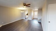 This two-story home offers a well-organized layout with thoughtfully updated finishes throughout both levels. The main living area is spacious and open, showcasing dark hardwood-style flooring that flows seamlessly from the entryway through to the living room. A ceiling fan with light fixture and an elegant chandelier provide both function and style overhead. A standout feature of the living room is the corner brick fireplace with a wood mantel, adding warmth and character to the space. Sliding glass doors lead to an outdoor area, allowing natural light to fill the room. The galley-style kitchen is efficiently designed with white cabinetry, granite countertops, a double sink, and black and stainless steel appliances, including a refrigerator, range, and built-in microwave. The main level also includes a half bathroom featuring a white vanity with granite countertop and a framed mirror. Upstairs, the bedrooms are carpeted for comfort, and one includes a walk-in closet with dual hanging rods and built-in shelving. A full bathroom on this level offers a tiled tub-shower combination with a built-in niche, white cabinetry, and a granite vanity top. The upper floor layout is clearly defined, with a staircase connecting both levels.