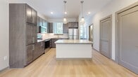 Located at 1801 Meridian St in Nashville, Tennessee, this contemporary two-story home offers a well-designed layout with modern finishes throughout. The main level features light hardwood flooring that flows through the open living areas, bathed in natural light from large windows. A staircase with warm wood railings connects the two floors, adding an inviting architectural detail to the space.

The kitchen is a standout feature, equipped with dark wood cabinetry, stainless steel appliances including a range, microwave, and refrigerator, and a classic white subway tile backsplash. A central island with a granite countertop and pendant lighting above serves as both a functional workspace and a focal point of the room.

The bathrooms mirror the kitchen's refined aesthetic, featuring dark wood vanities with granite countertops and clean white tiled tub-shower combinations with brushed nickel fixtures.

Upstairs, the bedrooms are finished with plush carpeting and feature impressively tall ceilings that create an airy, open feel. Each bedroom includes closet space, and the primary bedroom connects to a laundry area for added convenience.

Throughout the home, a neutral color palette of soft grays and warm whites creates a calm, cohesive ambiance well-suited for modern living in Nashville.