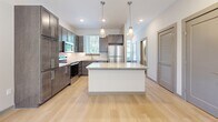 Located at 1801 Meridian St in Nashville, Tennessee, this contemporary two-story home offers a well-designed layout with modern finishes throughout. The main level features light hardwood flooring that flows through the open living areas, bathed in natural light from large windows. A staircase with warm wood railings connects the two floors, adding an inviting architectural detail to the space.

The kitchen is a standout feature, equipped with dark wood cabinetry, stainless steel appliances including a range, microwave, and refrigerator, and a classic white subway tile backsplash. A central island with a granite countertop and pendant lighting above serves as both a functional workspace and a focal point of the room.

The bathrooms mirror the kitchen's refined aesthetic, featuring dark wood vanities with granite countertops and clean white tiled tub-shower combinations with brushed nickel fixtures.

Upstairs, the bedrooms are finished with plush carpeting and feature impressively tall ceilings that create an airy, open feel. Each bedroom includes closet space, and the primary bedroom connects to a laundry area for added convenience.

Throughout the home, a neutral color palette of soft grays and warm whites creates a calm, cohesive ambiance well-suited for modern living in Nashville.