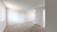 Located at 549 Sierra Vista Dr in Las Vegas, Nevada, this single-floor unit offers a straightforward and functional layout encompassing a living area, kitchen, bedroom, and bathroom. The living area features neutral-toned carpeting and light gray walls beneath a textured popcorn ceiling, creating a clean and understated atmosphere. Natural light filters in through vertical-blind-covered windows, lending a bright and open feel to the space. The compact kitchen is efficiently designed with white cabinetry extending to the ceiling for ample storage, a countertop with an integrated sink, an electric range, and a refrigerator, all set over wood-look tile flooring. The bedroom continues the carpeted flooring and includes a sliding-door closet with a hanging rod, offering practical storage. An adjacent bathroom is finished with wood-look tile flooring and features a combined tub and shower unit with a window above for natural ventilation and light. Throughout the unit, a consistent neutral color palette of whites and grays provides a cohesive and move-in-ready aesthetic, making it a practical and efficient living space in the heart of Las Vegas.