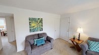Located at 755 E Main St in Greenwood, Indiana, this single-floor residence offers a well-organized layout that maximizes comfort and functionality. The carpeted living room provides a welcoming gathering space, featuring neutral walls, a textured ceiling, and room for both a sofa and loveseat arrangement. Natural light filters into the space, creating a bright and pleasant atmosphere throughout.

The kitchen is a practical and attractive area, outfitted with warm honey-toned wood cabinetry, dark granite-style countertops, and black appliances including an electric range, over-the-range microwave, and refrigerator, complemented by a white dishwasher. Recessed lighting and hardwood-style flooring add to the kitchen's polished appearance.

Adjacent to the kitchen, the dining area accommodates a full dining set and features a ceiling fan with light fixture, a window with outdoor views, and a textured ceiling, creating a comfortable space for meals.

The bedroom is a serene retreat with plush carpeting, a window allowing natural light, and ample space for bedroom furnishings. The full bathroom includes a tub and shower combination with grab bar, a toilet, and hardwood-style flooring, finished with a textured ceiling and clean white tilework.