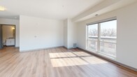 This three-bedroom, two-bathroom residence at 835 W Broadway Ave in Minneapolis offers a well-designed, single-floor layout with a clean, modern aesthetic throughout. The open-concept kitchen and living area serves as the heart of the home, featuring light wood cabinetry, granite countertops, stainless steel appliances including a dishwasher, range, and microwave, and hardwood-style flooring that extends throughout the main living spaces. Large windows and a sliding glass door in the living room fill the space with natural light and open onto a private balcony with views of the surrounding Minneapolis neighborhood.

The three bedrooms are comfortably sized, with the primary bedroom offering a dedicated closet and easy access to one of the two full bathrooms. Bedrooms are finished with neutral carpet, adding warmth underfoot. One bathroom features a tub-shower combination with a vanity, while the second includes a walk-in shower, both finished with light hardwood-style flooring and clean, neutral tones. Two closets provide practical storage throughout the unit.

The overall ambiance is bright and contemporary, with a neutral color palette of whites and light grays that creates a versatile and inviting living environment suitable for a range of lifestyles.