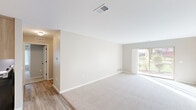 This well-appointed 2-bedroom, 2-bathroom single-story home in Harrison Township, Michigan offers a thoughtfully designed layout with a clean, neutral aesthetic throughout. The open living room is bright and welcoming, featuring plush carpeting, crisp white trim, and a sliding glass door that invites natural light and provides outdoor views. An adjacent hallway connects the main living areas to the private quarters of the home.

The kitchen is finished with warm wood cabinetry, white countertops, wood-look hard surface flooring, and stainless steel appliances including a refrigerator and dishwasher, offering both style and functionality. The living and kitchen areas flow naturally, making the space practical for everyday use.

The spacious primary bedroom features carpeted floors, neutral walls, and direct access to a well-sized walk-in closet area. The second bedroom also offers generous proportions with dual closets and a window with a built-in ledge. Both rooms are finished in soft, neutral tones.

Both bathrooms are appointed with warm wood vanities, white quartz-style countertops, and elegant marble-style porcelain tile flooring. The primary bath includes a glass-enclosed shower, while the second bath features a clean, open layout. The overall ambiance of the home is calm, modern, and move-in ready.