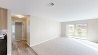 This well-appointed 2-bedroom, 2-bathroom single-story home in Harrison Township, Michigan offers a thoughtfully designed layout with a clean, neutral aesthetic throughout. The open living room is bright and welcoming, featuring plush carpeting, crisp white trim, and a sliding glass door that invites natural light and provides outdoor views. An adjacent hallway connects the main living areas to the private quarters of the home.

The kitchen is finished with warm wood cabinetry, white countertops, wood-look hard surface flooring, and stainless steel appliances including a refrigerator and dishwasher, offering both style and functionality. The living and kitchen areas flow naturally, making the space practical for everyday use.

The spacious primary bedroom features carpeted floors, neutral walls, and direct access to a well-sized walk-in closet area. The second bedroom also offers generous proportions with dual closets and a window with a built-in ledge. Both rooms are finished in soft, neutral tones.

Both bathrooms are appointed with warm wood vanities, white quartz-style countertops, and elegant marble-style porcelain tile flooring. The primary bath includes a glass-enclosed shower, while the second bath features a clean, open layout. The overall ambiance of the home is calm, modern, and move-in ready.
