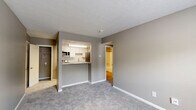 Located at 9115 Knights Bridge Blvd in Indianapolis, IN, this one-bedroom, one-bathroom unit offers a well-designed, single-floor layout that maximizes every square foot. The open living area is finished with soft gray carpet and neutral taupe walls, creating a calm and cohesive atmosphere throughout. A textured ceiling and clean white baseboards add subtle architectural detail.

The kitchen is neatly defined by a pass-through design with a granite-topped breakfast bar, white cabinetry, a tile backsplash, and stainless steel appliances including a refrigerator, electric range, and over-the-range microwave. Light wood-style flooring grounds the kitchen space and connects seamlessly to the hallway.

The bedroom features plush carpet, a natural light-filled window with blinds, and access to a dedicated closet with a wire shelving system, providing practical storage. A second closet offers additional storage elsewhere in the unit.

The bathroom is finished with light wood-style flooring, a full soaking tub with a curved shower rod, and neutral gray walls. A utility room rounds out the functional layout. The unit also includes an in-unit security system panel, adding a layer of convenience and peace of mind.
