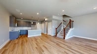 Located at 3813 Broadway Ave in Grand Prairie, TX, this contemporary three-story home offers 3 bedrooms, 4 bathrooms, and a well-designed layout spread across three distinct floors. The main level greets you with an open-concept living and kitchen area finished with warm luxury vinyl plank flooring. The kitchen is a standout, featuring grey shaker-style cabinetry, a white subway tile backsplash, light quartz countertops, stainless steel appliances, pendant lighting, and a large center island with a built-in sink — ideal for both cooking and entertaining. The living area is bright and open, with recessed lighting and a staircase featuring rich wood newel posts and sleek metal balusters. The second floor hosts the primary bedrooms and additional bathrooms. Bedrooms are carpeted and filled with natural light from large windows, with ceiling fans providing comfort. The bathrooms are finished with large-format marble-look tile, grey vanity cabinetry, quartz countertops, and glass-enclosed showers or soaking tub combinations. A dedicated laundry room with upper cabinetry and hardwood-style flooring adds everyday convenience. The third floor offers additional flexible living space. Neutral grey walls and consistent finishes unify the home's modern, clean aesthetic throughout.