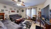 Located at 1300 Hazel Ln in Farmington, MO, this single-floor home offers a practical and comfortable layout across two bedrooms, two bathrooms, a kitchen, living room, and a dedicated office space. The living room is a welcoming area featuring light tile flooring, a ceiling fan with light fixture, and windows dressed with sheer curtains that allow natural light to fill the room. An electric fireplace built into a rich wood entertainment console serves as a focal point on the opposite wall. The kitchen is well-equipped with warm cherry wood cabinetry, dark granite-style countertops, a dining table with seating, and tile flooring — providing ample storage and prep space. The primary bedroom includes a ceiling fan, carpet flooring, and enough space to accommodate a full bedroom suite. The second bedroom offers carpeted floors and a curtained window. The office is a versatile room with carpet, a ceiling fan, a window for natural light, and space for a desk and exercise equipment. The bathroom features a wood vanity with a large mirror, a tub-shower combination, and tile flooring.