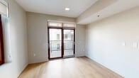 Located at 4545 Laclede Ave, Unit 401 in the Central West End neighborhood of St. Louis, Missouri, this single-floor residence combines modern design with functional living. Light-toned hardwood flooring runs throughout the entire unit, creating a cohesive and inviting aesthetic.

The kitchen is a standout feature, showcasing high-gloss gray cabinetry, a dark granite island and countertops, a bold black tile backsplash, and a full suite of stainless steel appliances. Dramatic pendant lighting with gold-accented interiors adds a contemporary flair to the space.

The living and sleeping areas are bright and open, with neutral warm-toned walls and recessed lighting. One room features sliding glass doors with transom windows that open directly onto a private balcony with metal railing, offering views of the surrounding neighborhood. Additional rooms benefit from large dark-framed windows that invite natural light and provide urban views.

The bathroom is cleanly designed with large-format gray tile in the tub and shower surround, matte black fixtures and hardware, light wood-tone flooring, and a white vanity with granite countertop. A wide hallway connects the rooms, contributing to the open and airy feel of the overall layout.