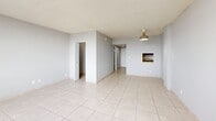Located at 14795 NE 18th Ave in North Miami, FL, this single-floor studio unit offers a straightforward and functional layout across a compact footprint. The space is organized into a living area, entrance, closet, and full bathroom, making efficient use of every square foot.

The living area is bright and open, finished with light-toned ceramic floor tiles that run throughout the unit, contributing to a clean and cohesive aesthetic. Neutral gray walls and a textured ceiling create a simple, understated backdrop. A wall-mounted pendant light fixture adds a subtle design touch, while a built-in wall niche provides a unique architectural detail and convenient display space. A wall-unit air conditioner ensures year-round climate comfort.

Large horizontal windows flood the living area with abundant natural light and frame views of the surrounding North Miami cityscape, enhancing the sense of openness within the space. The kitchen area includes base cabinetry and space for standard appliances including a range and refrigerator.

The bathroom is finished with a clean, white tub-shower combination with tiled surround, complemented by chrome fixtures. A dedicated closet offers practical storage. The entrance provides a clear transition into the main living space, completing this straightforward and livable unit.