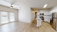 Located at 7750 Belfort Pkwy in Jacksonville, Florida, this single-floor unit offers a clean, modern design with a cohesive neutral palette and light wood-look flooring throughout. The open-concept living and kitchen area creates a spacious, airy feel, with natural light flowing in from multiple windows. Ceiling fans are present in the living and bedroom areas, adding to everyday comfort.

The kitchen is a standout feature, boasting crisp white cabinetry, a classic subway tile backsplash, light quartz-style countertops, and a full suite of stainless steel appliances including a refrigerator, range, microwave, and dishwasher. A central island provides additional prep and seating space, while an adjacent walk-in pantry offers generous storage. The kitchen opens seamlessly to the living area, making it ideal for entertaining.

The bedrooms are well-proportioned, each featuring wood-look flooring, ceiling fans, and windows with views of surrounding greenery. Two bathrooms mirror the home's design aesthetic, with white vanity cabinetry, light countertops, brushed nickel fixtures, and tiled tub-shower combinations. A dedicated laundry room with full-size washer and dryer adds practical convenience. Overall, the unit presents a bright, functional, and well-designed living environment.