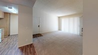 Located at 401 W Orangewood Ave in Anaheim, California, this single-floor residence offers a well-organized and functional layout. The living area is generously sized, featuring plush carpeting, a ceiling fan, and a large window with vertical blinds that allows abundant natural light to fill the space. Wood-style flooring in the entryway and adjoining areas adds a warm contrast to the soft carpet throughout the bedrooms and living spaces.

The galley-style kitchen is efficiently designed with warm wood cabinetry, granite-style countertops, and white appliances including an electric range, built-in microwave, and dishwasher. Wood-look flooring runs the length of the kitchen, complementing the clean, practical layout.

The bedrooms are carpeted and bright, each with windows dressed in vertical blinds that invite natural light and outdoor views of surrounding greenery. One bedroom features a spacious walk-in closet, offering excellent storage. The bathroom vanity areas are finished with granite-style countertops and warm wood cabinetry. Two bathrooms are present — one with classic white tile surrounding the tub-shower combo, and another featuring stylish sage-green subway tile for a more updated aesthetic. The textured ceilings throughout give the space a consistent, finished character.