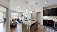 Located at 6010 Attleboro Dr in Cary, NC, this well-appointed 2-bedroom, 2-bathroom residence offers a thoughtfully designed single-level layout. The open-concept living and kitchen area serves as the heart of the home, where a granite-topped island with pendant lighting and an undermount sink flows seamlessly into the living room. The kitchen features dark cabinetry, subway tile backsplash, stainless steel appliances, and generous counter space. The living room is bright and inviting, with a sliding glass door opening to a private balcony, a bold accent wall, and wood-style flooring that extends throughout the home. The spacious primary bedroom includes a ceiling fan, large windows with outdoor views, and a dedicated closet. The second bedroom is equally well-lit, with oversized windows and its own closet. Both bathrooms are finished with dark espresso vanities, white countertops, large framed mirrors, and wood-style tile flooring; the primary bath features a glass-enclosed shower. Additional highlights include a welcoming entryway with open wall space, in-unit laundry, and a neutral color palette that creates a clean, modern ambiance throughout.