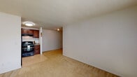 Located at 3990 Harmony Dr in Colorado Springs, Colorado, this single-floor residence offers a practical and comfortable layout across its living spaces. The open living area features warm, neutral-toned carpeting and clean white walls beneath a textured ceiling, creating a bright and welcoming atmosphere. Large windows fitted with vertical blinds allow natural light to fill the space throughout the day.

The kitchen is well-appointed with rich dark wood cabinetry, light granite-style countertops, a stainless steel sink, and black appliances including a freestanding electric range with overhead ventilation and a full-size refrigerator. Tile flooring in the kitchen provides a clean transition from the carpeted living and bedroom areas.

The bedrooms are generously proportioned, each offering neutral carpet, natural light from windows with vertical blinds, and textured ceilings with flush-mount lighting. The layout accommodates a variety of furniture arrangements.

The bathroom is clean and functional, featuring a tiled tub-shower combination with a curtain, a wall-mounted sink, a toilet, and a large mirror above the vanity area. Tile flooring completes the space. Overall, the unit presents a straightforward and livable design well-suited for everyday comfort in Colorado Springs.