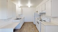 Located at 416 E Novak Ln in Kent, Washington, this single-floor unit offers a practical and functional layout across three bedrooms, a combined kitchen and living room, and a connecting hallway. Wood-style flooring runs consistently throughout the space, lending a cohesive and clean aesthetic to every room.

The living room is an open, well-proportioned area filled with natural light from a large sliding glass door fitted with vertical blinds, which also provides direct outdoor access. Baseboard heating units are positioned along the walls, ensuring efficient climate control. The entry hallway connects the living area to the rest of the unit in a straightforward layout.

The kitchen is designed for functionality, featuring white cabinetry along both walls, light countertops, a stainless steel sink, a white electric range with overhead ventilation, and a full-size refrigerator. Globe-style ceiling fixtures provide ample overhead lighting, and a window with vertical blinds brings in natural light.

Each of the three bedrooms maintains the same wood-style flooring and neutral white walls. The bedrooms include windows that allow natural light and outdoor views, closets with sliding panel doors and hanging rods, and baseboard heaters. The primary bedroom offers a comfortable and versatile footprint suitable for standard furnishings.