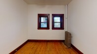 Located at 214 W 15th St in Minneapolis, Minnesota, this single-floor unit showcases a blend of classic character and functional design. Throughout the space, warm hardwood floors and rich, dark-stained wood trim and door casings lend a timeless aesthetic that ties each room together cohesively.

The living areas are bright and open, with white walls providing a clean backdrop that highlights the natural warmth of the wood flooring. Ceiling fans are present in multiple rooms, offering both comfort and light. Windows framed in dark wood trim allow natural light to filter in while offering views of the surrounding neighborhood.

One of the standout features is the bathroom, which exudes vintage charm with its classic black-and-white checkered tile floor, a pedestal sink, and a freestanding clawfoot bathtub — a distinctive nod to period craftsmanship. A framed mirror above the sink and a small window round out the space.

Additional rooms offer comfortable proportions, with one featuring a cast-iron radiator that speaks to the building's historic character. Deep baseboards complement the wood trim found throughout. The entry area includes a solid wood door with warm-toned casing, creating a welcoming transition into the unit. Overall, the space presents a well-preserved interior rich with architectural detail and classic Minneapolis character.