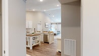 This single-story, 2-bedroom, 3-bathroom home offers a thoughtfully designed layout with modern finishes throughout. The open-concept kitchen and living area serves as the heart of the home, featuring vaulted ceilings that enhance the sense of space. The kitchen is equipped with stainless steel appliances, white shaker-style cabinetry, a subway tile backsplash, and a peninsula with bar seating—ideal for casual dining. Wood-look luxury vinyl plank flooring flows consistently through the main living areas, adding warmth and cohesion.

The living room connects seamlessly to an additional room via a striking set of white double barn doors on a black sliding track, providing flexible, open living or privacy as needed. This secondary space features a ceiling fan and natural light from a window with blinds.

The primary bedroom is a comfortable retreat, while the second bedroom offers its own ceiling fan and natural light. Three bathrooms serve the home, each finished with white vanities and wood-look flooring. A dedicated laundry room includes a full-size washer and dryer with overhead cabinetry for storage. Two closets provide ample organizational space throughout the home.