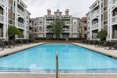 Located in Sandy Springs, GA, this meticulously maintained outdoor courtyard space offers a resort-style atmosphere designed for relaxation and leisure. At its centerpiece sits a generously sized swimming pool with crystal-clear blue water, framed by a smooth concrete pool deck lined with dark lounge chairs — ideal for sunbathing or unwinding outdoors.

The surrounding landscape is thoughtfully curated, featuring neatly trimmed hedgerows, ornamental trees with decorative river rock bases, and a rich variety of plantings including colorful shrubs, lush ground cover, and seasonal flowering plants. Wide, smooth walkways wind through the greenery, leading toward a welcoming entrance staircase flanked by tall trees and vibrant garden beds.

The multi-story buildings enclosing the courtyard feature warm taupe siding, white-trimmed balconies, and large windows that overlook the outdoor space, creating a cohesive and inviting architectural backdrop. The overall ambiance strikes a balance between polished and approachable, offering residents a tranquil outdoor retreat within a well-kept community setting in the heart of Sandy Springs.