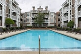 Located in Sandy Springs, GA, this meticulously maintained outdoor courtyard space offers a resort-style atmosphere designed for relaxation and leisure. At its centerpiece sits a generously sized swimming pool with crystal-clear blue water, framed by a smooth concrete pool deck lined with dark lounge chairs — ideal for sunbathing or unwinding outdoors.

The surrounding landscape is thoughtfully curated, featuring neatly trimmed hedgerows, ornamental trees with decorative river rock bases, and a rich variety of plantings including colorful shrubs, lush ground cover, and seasonal flowering plants. Wide, smooth walkways wind through the greenery, leading toward a welcoming entrance staircase flanked by tall trees and vibrant garden beds.

The multi-story buildings enclosing the courtyard feature warm taupe siding, white-trimmed balconies, and large windows that overlook the outdoor space, creating a cohesive and inviting architectural backdrop. The overall ambiance strikes a balance between polished and approachable, offering residents a tranquil outdoor retreat within a well-kept community setting in the heart of Sandy Springs.