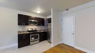 Located at 236 W Walnut Lane in the Germantown neighborhood of Philadelphia, PA, this single-floor unit offers a thoughtfully designed living space with modern finishes throughout. The kitchen is a standout feature, showcasing rich dark cabinetry paired with granite countertops and a classic tile backsplash. A full suite of stainless steel appliances — including a gas range, built-in microwave, and refrigerator — provides both style and functionality. The kitchen flows naturally toward the entryway, which features a solid white entry door with secure hardware, creating a welcoming and practical arrival point. Warm hardwood flooring extends through the living areas, adding character and continuity to the space, while light-toned flooring in the kitchen complements the overall aesthetic. Neutral wall tones keep the interior feeling bright and open, allowing the design elements to take center stage. The layout is efficient and well-organized, making excellent use of the available space. With its contemporary finishes and practical design, this unit offers a comfortable and modern living environment in a well-established Philadelphia neighborhood.