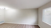 This single-floor space offers a clean, updated interior with a neutral color palette and a mix of hard-surface and carpeted flooring throughout. The living area is bright and welcoming, featuring wood-look plank flooring, crisp white trim, and a window with blinds that allows natural light to fill the space. A front entry door opens directly into this area, providing a straightforward and functional layout. The kitchen is a standout feature, designed in a galley style with two-toned cabinetry — white upper shaker-style cabinets paired with gray lower cabinets — and marble-look countertops. Black hardware and fixtures add a modern contrast. The kitchen is well-equipped with stainless appliances including a refrigerator, microwave, and range, as well as a stainless sink and a dishwasher. In-unit laundry is conveniently integrated into the kitchen space. The bedroom features plush carpeting and neutral walls, offering a comfortable and quiet retreat. The bathroom includes a full tub and shower combo with white tile surround, a toilet, and a vanity with matching gray cabinetry, complemented by black hardware details. Overall, the space presents a cohesive, move-in-ready aesthetic with thoughtful updates and practical amenities throughout.