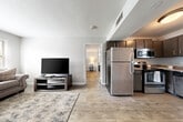 Located in Red Bank, TN, this single-floor unit offers a thoughtfully designed layout with modern finishes throughout. The kitchen is equipped with a full suite of stainless steel appliances—including a refrigerator, electric range, microwave, and dishwasher—complemented by gray cabinetry, granite-style countertops, and a window that brings in natural light. The open-plan living and dining area flows directly from the kitchen, creating a connected, functional space with warm hardwood-style flooring underfoot.

The bedroom is generously proportioned and features a ceiling fan with light fixture, a dedicated closet, and direct access to an en-suite area with a vanity featuring dark cabinetry and a white countertop. A window allows natural light to fill the room, adding to its bright and airy feel. A separate dedicated laundry room provides washer and dryer hookups, built-in shelving, and an electrical panel, offering practical utility space. Consistent light-toned hardwood-style flooring, neutral gray walls, and clean white trim run throughout the unit, lending a cohesive and contemporary aesthetic to every room.