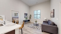 Located at 340 E Fulton St in Columbus, Ohio, this 2-bedroom, 2-bathroom residence offers a well-designed single-floor layout with impressively tall ceilings throughout, creating a bright and airy atmosphere. The open-concept kitchen and living area serves as the heart of the home, where rich dark-cabinetry contrasts elegantly with white quartz countertops. A central peninsula with seating doubles as a breakfast bar, ideal for casual dining. Stainless steel appliances, including a range, microwave, refrigerator, and dishwasher, complete the modern kitchen. Light wood-tone flooring runs seamlessly throughout, adding warmth and continuity. The living room benefits from a large window that draws in natural light and frames views of the surrounding neighborhood. Both bedrooms are comfortably sized, featuring the same soaring ceilings and light flooring, with the primary bedroom offering direct access to its own bathroom. Each bathroom is appointed with dark vanity cabinetry, white countertops, tiled tub-shower combinations, and wood-look tile flooring. Three closets provide ample storage, and a dedicated laundry area adds everyday convenience. The overall aesthetic is clean, contemporary, and well-finished throughout.