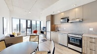 Located in the heart of Ottawa at 75 Slater Street, this modern 3-bedroom, 1-bathroom unit offers a thoughtfully designed layout across a single floor. The open-concept living and kitchen area is anchored by expansive floor-to-ceiling windows that flood the space with natural light and frame sweeping views of the Ottawa skyline. Light hardwood flooring runs throughout, complementing the clean white walls and exposed concrete ceiling details that lend an industrial-modern character to the space.

The kitchen features sleek two-tone cabinetry in warm wood and soft grey tones, a marble-effect tile backsplash, stainless steel appliances, and ample counter space — all seamlessly integrated into the open living area. The dining space flows naturally from the kitchen, creating a cohesive area ideal for daily living and entertaining.

The living room benefits from floor-to-ceiling glazing and direct city views, creating a bright and airy atmosphere. Each of the three bedrooms is well-proportioned, with the primary bedroom offering generous space, large windows with city outlooks, and abundant natural light.

The bathroom is finished with elegant marble-style wall tiles, hexagonal mosaic floor tiles, a soaker tub with an overhead rain shower, and matte black fixtures. Connected by light-filled hallways with warm wood-toned doors, this unit delivers a polished, contemporary urban living experience.