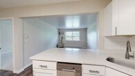 This single-floor, one-bedroom, one-bathroom residence offers a practical and functional layout with thoughtfully designed spaces throughout. The kitchen is a standout feature, equipped with crisp white shaker-style cabinetry, a white subway tile backsplash, and a full suite of stainless steel appliances including a refrigerator, electric range, and over-the-range microwave. Wood-look plank flooring runs through the kitchen and living areas, lending a warm, cohesive feel to the space. The living room is bright and open, featuring neutral walls, baseboard heating, and a clean, versatile canvas for various furniture arrangements. Natural light filters in through windows that offer views of surrounding greenery, adding a welcoming, airy quality to the interior. The bedroom is generously sized and finished with plush carpeting and a window that brings in natural light, creating a comfortable and restful retreat. A baseboard heating unit ensures year-round comfort. The bathroom includes a full tub-shower combination, toilet, and wood-look flooring, finished in a clean, neutral palette. Throughout the residence, neutral tones and clean lines create a consistent, move-in-ready aesthetic that is both practical and inviting.